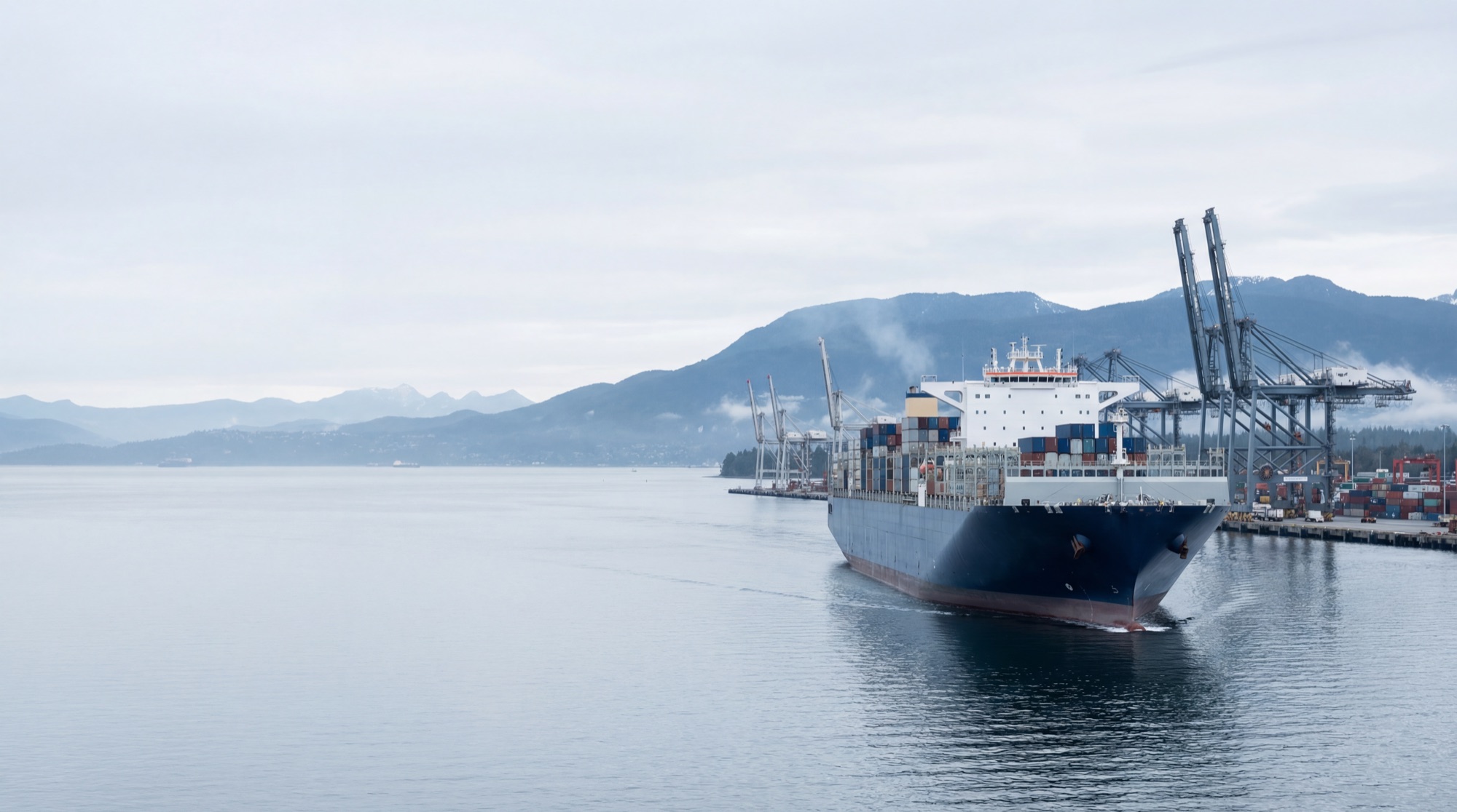 Modern container vessel arriving at the Port of Vancouver with North Shore mountains in the distance
